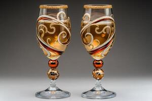 Two elegant wine glasses decorated with gold and copper ornaments containing white wine photo