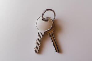 Two metal keys on key ring resting on white surface photo