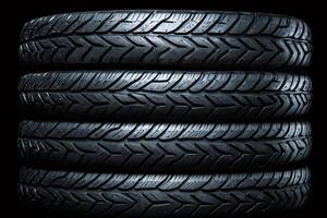 Wet car tires stacked on black background showing tread pattern photo
