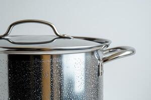 Steaming stainless steel cooking pot with lid and water droplets on white background photo