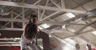 Sportswoman doing exercise with battle rope under roof video