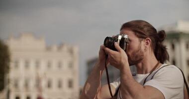 Smiling male tourist admiring sightseeing and taking photos on retro camera video