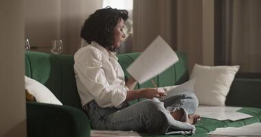 Barefoot architect working with drafts on sofa video