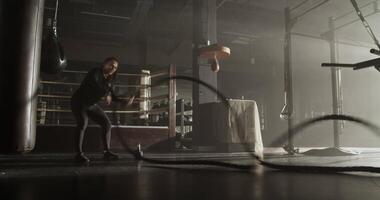Powerful female athlete exercising with battle ropes in gym video