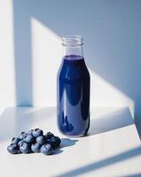 Blueberry juice in a glass bottle on a table photo