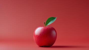 there is a red apple with a green stem on a red surface photo
