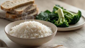 A bowl of rice with a side of vegetables and bread photo
