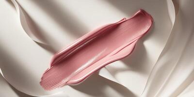 A pink lipstick is laying on a white surface photo