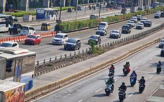 Jakarta, Indonesia on 8 July 2024. Busy Indonesian Highway with Diverse Vehicles and Traffic Barriers photo