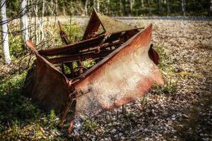 Historic rusty snow plow lying in the forest photo