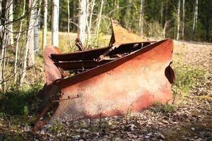 Historic rusty snow plow lying in the forest photo