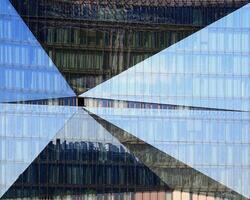 Modern glass facade in Berlin with reflections of skyline and pavement photo