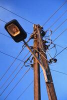 Old street lamp with power cables in warm evening light photo