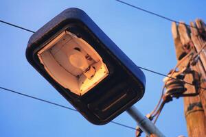 Old street lamp with power cables in warm evening light photo