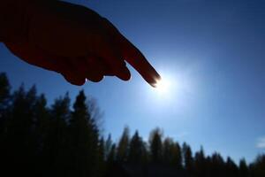 Pointing at the sun on a clear blue sky photo