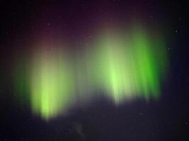 Green and red aurora borealis on night sky photo