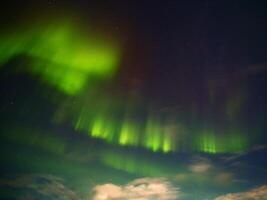 Green and red aurora with clouds in the night photo