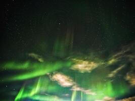 Conceptual shot of stars with aurora and clouds, rotating around the north photo