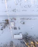 Drone shot directly downward snow covered group of houses with patches of sunlight photo