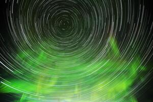 Star trails rotating around the north, with aurora and clouds photo