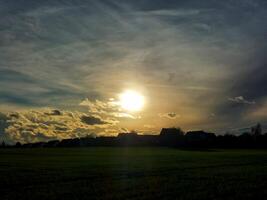 Row of houses on field in backlit evening scene photo