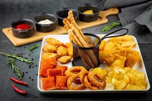 beer set with nuggets, breaded onion rings, fries and sauces side view photo
