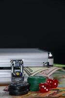 A silver case sits on top of several dollar bills with poker chips, dice, and a few more bills surrounding it photo