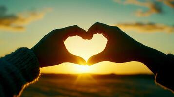 Two hands create a heart shape against a beautiful sunset background in a field of flowers, Couple making heart with hands. photo