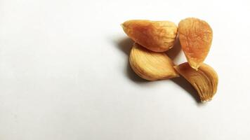 Garlic that turns into golden garlic has a slightly transparent golden yellow color, with a soft texture that tends to be sticky. Golden garlic isolated on white background. photo