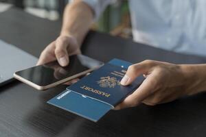 Hand Man Online booking and buying plane tickets using laptop phone and credit card Planning trip travel vacation with passport and ticket photo