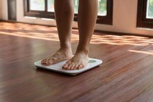 Fat diet and scale feet standing on electronic scales for weight control. Measurement instrument in kilogram for a diet control photo