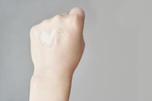 Close up of clear serum on female caucasian hand with light background. photo