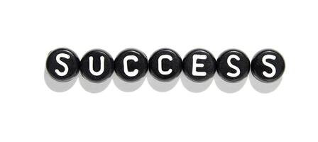 Minimalist alphabet beads arranged to spell success on white background for motivation and achievement concepts photo
