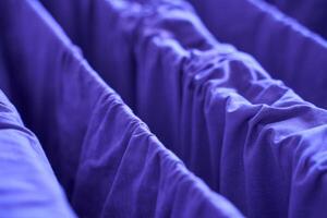 Blue fabric curtains close up showing texture and folds in a dimly lit setting. photo
