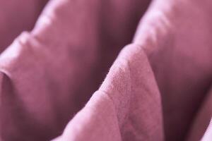 Close up of soft pink fabric with draped folds creating a textured abstract pattern. photo