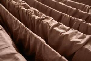 Close up of brown fabric with gathered texture and parallel folds creating a cozy and warm textile pattern. photo