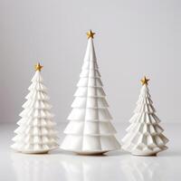 three Christmas white porcelain fir trees with a gold star on the top of their heads of different sizes on a white background. Scandinavian style photo