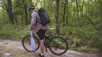 Volunteer bicyclist remove trash bags for garbage, clean up forest during bicycle ride. Save environment. Recycle waste litter rubbish garbage trash junk clean training. Picking up trash while cycling video