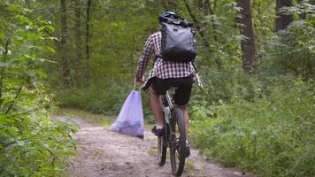Pollution. Ecological problem. Male cyclist carry garbage bag on handlebars bicycle after removing pollution. Male collects garbage during eco marathon, cleaning plastic bottles and other garbage. video
