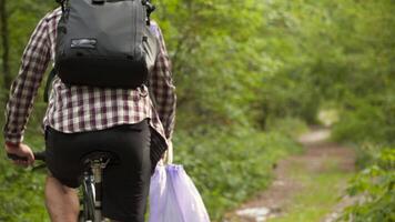 Volunteer bicyclist remove trash bags for garbage, clean up forest during bicycle ride. Save environment. Recycle waste litter rubbish garbage trash junk clean training. Picking up trash while cycling video