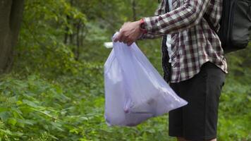 A bad man throws garbage out of a plastic trash bag in the forest. The male intruder leaves litter trash and walks away. Pollution and ecological problem, plastic recycling, pollution of nature. video