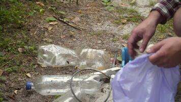 Safe planet, man hiker with backpack collects garbage in plastic trash bag in forest for clean planet, environment and ecology while walking in nature. Green volunteering. Man hand picking up garbage. video