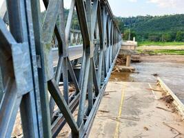 Steel bridge structure over a partially damaged or flooded river with debris accumulated below. A scene depicting infrastructure and natural forces, ideal for themes of construction, flood aftermath photo