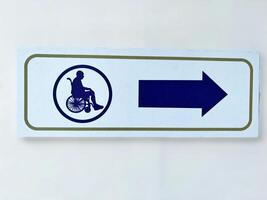 Directional sign for wheelchair users featuring a bold arrow pointing right. The symbol ensures accessibility and clear guidance in public spaces, promoting inclusivity and convenience for individuals photo