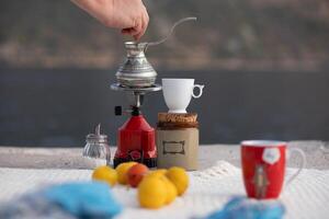 Brewing coffee by the water at sunset with a scenic view of Montenegro and fresh fruit on a cozy table, creating a relaxing atmosphere for enjoyment and reflection on a peaceful day photo