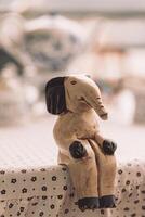 Stone statuette of anthropomorphic elephant sitting on table edge with tablecloth photo