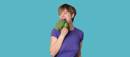 Broccoli in the hand of a slender smiling woman on a blue background. A panoramic banner with a place for your text. healthy lifestyle. photo