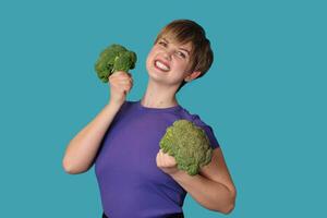 Broccoli in the hand of a slender smiling woman on a blue background. healthy lifestyle. photo
