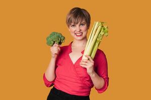 Smiling slender Caucasian girl with green vegetables in her hands, broccoli and celery, Organic vegetables. photo