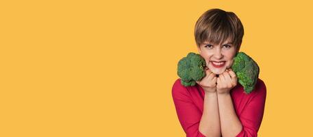 In the studio shot, a young Caucasian woman holds fresh broccoli in her hands. of the healthy eating concept. A place for your text. Panoramic banner. photo